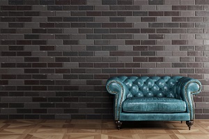 blue brown leather armchair standing in front of black brick wall with copy space