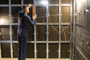 man installing soundproof acoustic art paneling in building