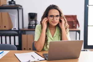 woman working at the office wearing glasses covering ears with fingers with annoyed expression for the noise of loud music