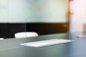 close up of acrylic plexiglass separator standing partition wall with pass-through on the desk in the meeting room