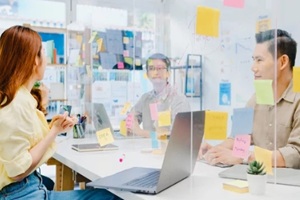 businesspeople discussing business brainstorm meeting together share data and write on acrylic partition stand back in new normal office