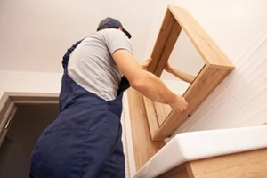 man installing a acrylic mirror in a wooden frame