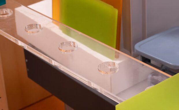 acrylic display stand with colorful plastic sheets in various sizes arranged on a wooden surface in a well-lit indoor setting
