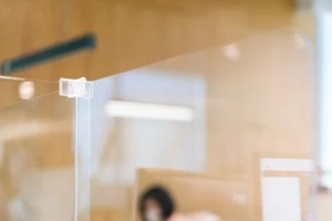 acrylic plexiglass separator setting on the desk in the office with blur employee wearing mask