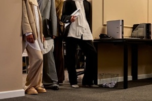 professional women in suits and hijabs leaning against an office wall with files and papers