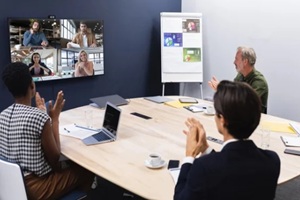 diverse group of business colleagues having video call with coworkers on screen in meeting room