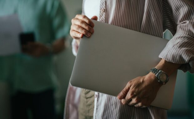 woman holding laptop walking in modern office workspace