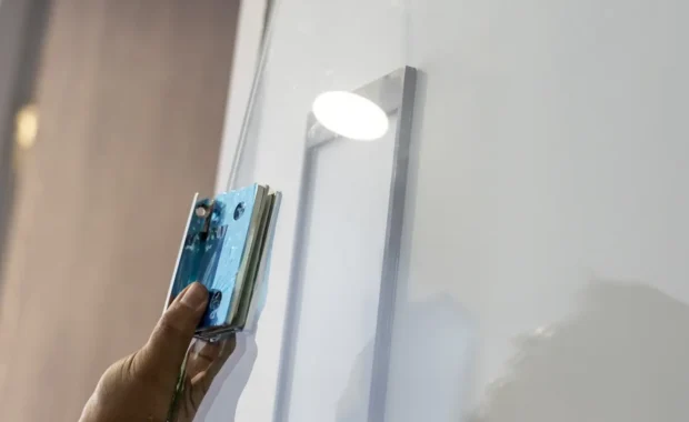 careful focused worker hand holding tool during glass installation for shower divider in modern bathroom interior home renovation project